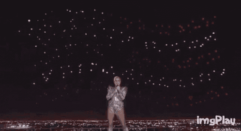 a man is standing in front of a fireworks display with imgplay written below him