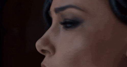 a close up of a woman 's face with blue eyes and black eyeshadow