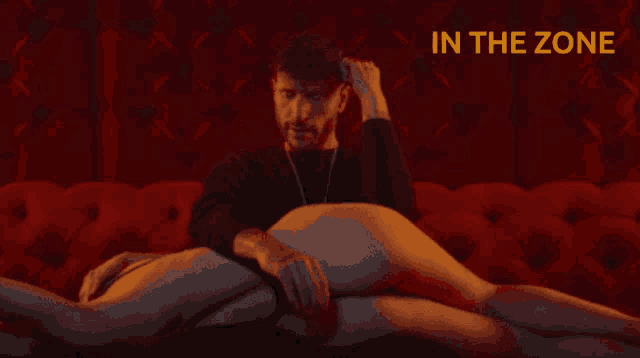 a man sits on a red couch with a woman laying on top of him and the words in the zone above him