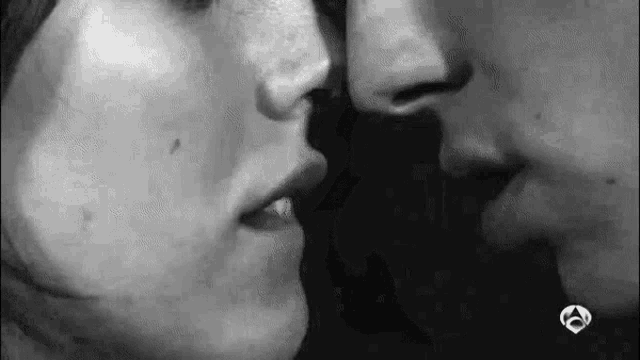 a black and white photo of a man and woman kissing each other .