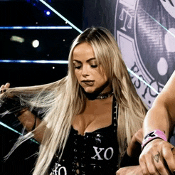 a blonde woman wearing a black top with xo written on it