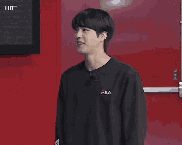 a young man in a black sweatshirt is standing in front of a red door .