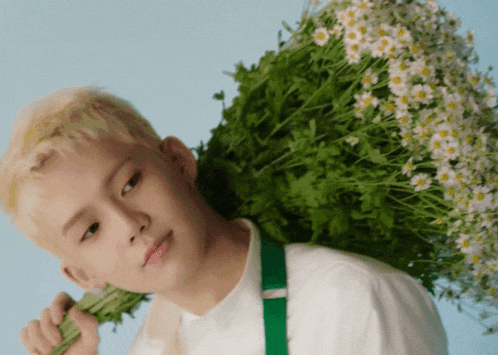 a young man carrying a bunch of flowers on his shoulder