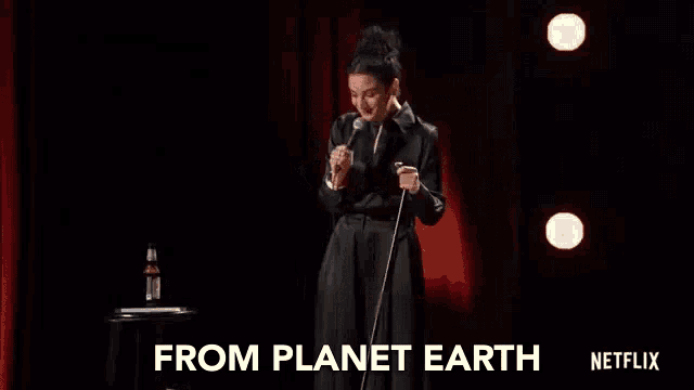 a woman is standing in front of a microphone on a stage and giving a speech .