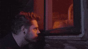 a man looking out a window with a reflection of himself in it