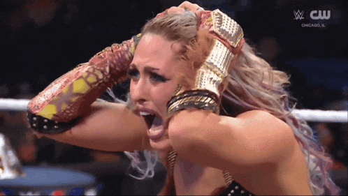 a woman in a wrestling ring with a cw logo on the bottom
