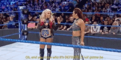 two women are in a wrestling ring talking to each other .