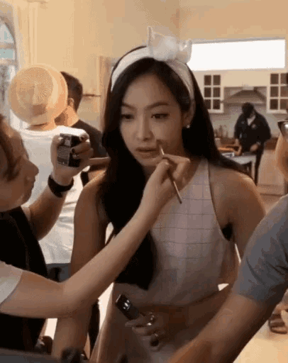 a woman is getting her makeup done by a woman wearing a white headband