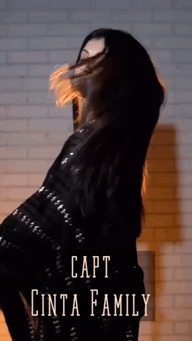a woman in a black dress is dancing in front of a brick wall with the caption capt cinta family on the bottom