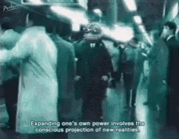 a group of people are walking down a street and a man is standing in the middle of the crowd .