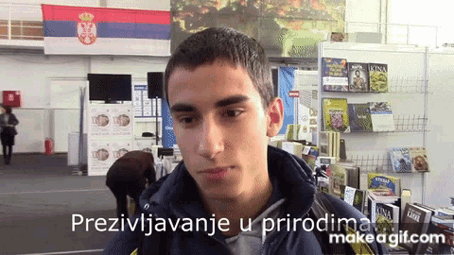 a young man stands in front of a display of books with the words prezivljavanje u prirodnima make a gif.com