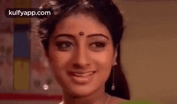a close up of a woman smiling with her eyes closed and a bindi on her forehead .