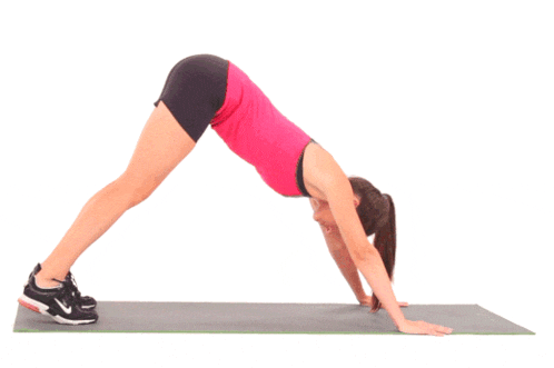 a woman in a pink tank top and black shorts is doing a yoga pose on a mat
