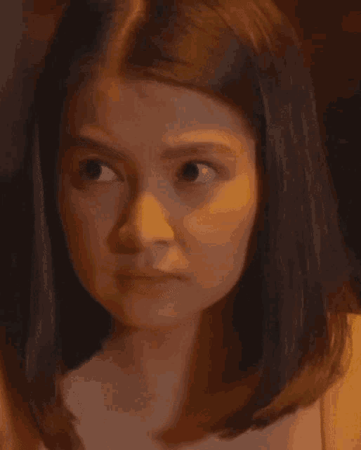 a close up of a woman 's face with her eyes closed and a sad look on her face .
