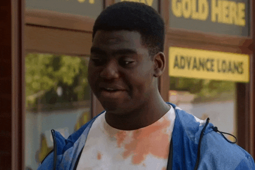 a man in a blue jacket is standing in front of a gold here advance loans store .