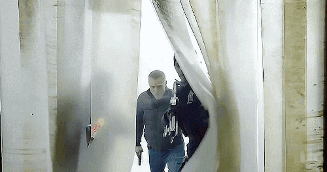 a man is holding a gun in a hallway