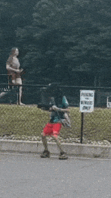 a person is walking down the street in front of a sign that says parking for visitors only