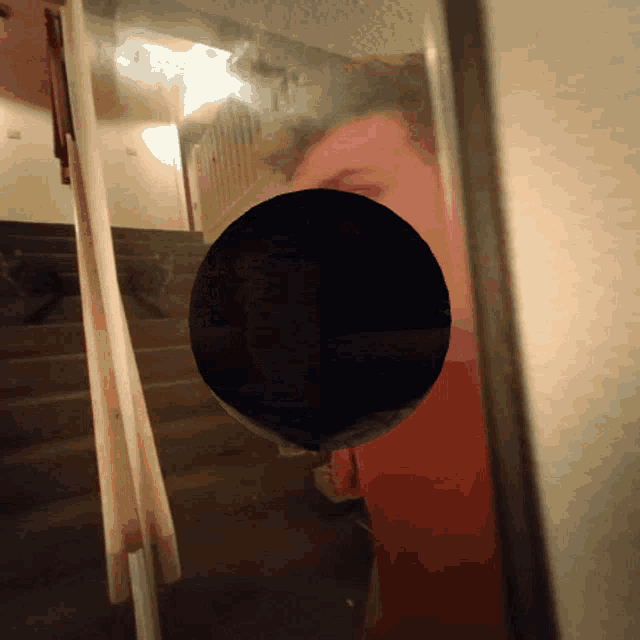 a reflection of a person 's face in a mirror with a black circle in the middle
