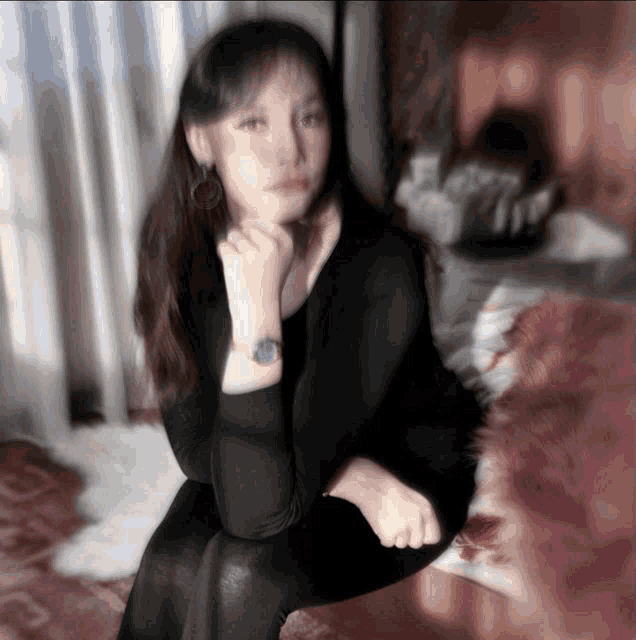 a woman wearing a watch sits on a couch