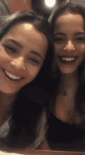 two women are smiling for the camera and one is wearing a black shirt
