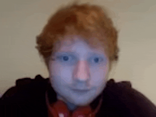 a blurry picture of a man 's face with red hair and headphones on .