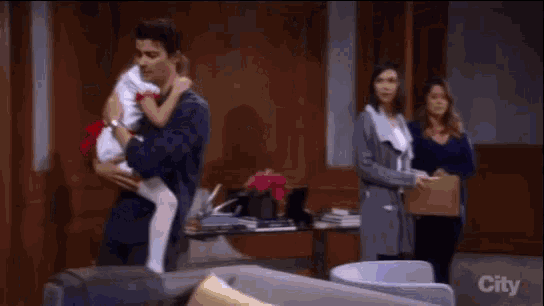 a man is holding a little girl in his arms while a woman stands behind him .
