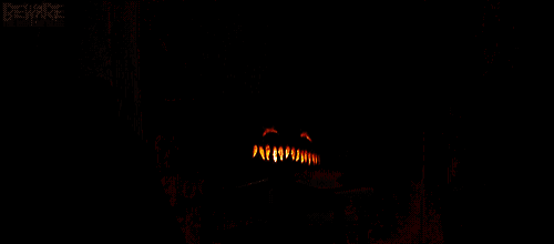 a carved pumpkin is burning in front of a wall that has beware written on it