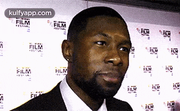 a man in a suit and tie is standing in front of a wall with film festival logos .