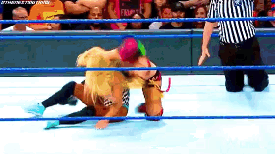 two women are wrestling in a wrestling ring with a referee watching .