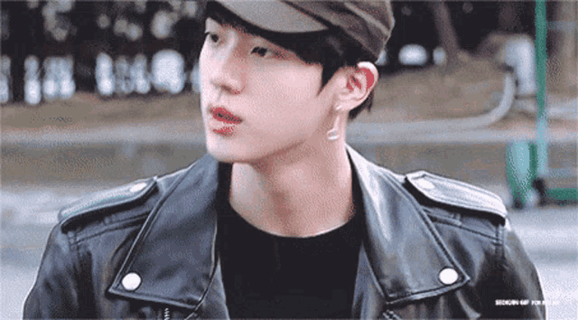 a close up of a man wearing a hat and a leather jacket .
