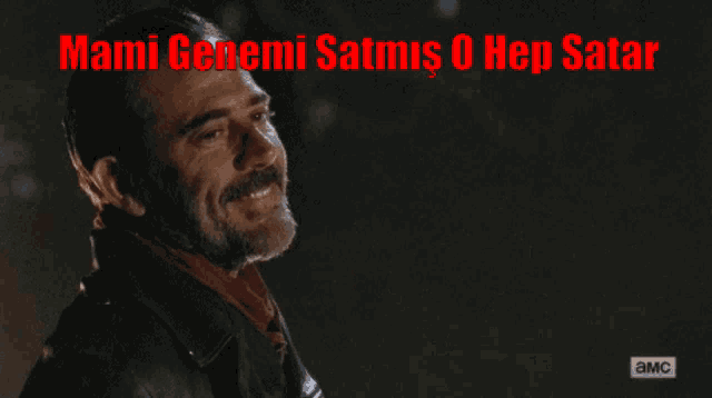 a man with a beard is smiling in front of a sign that says ' mami genemi satmus 0 hep satar '