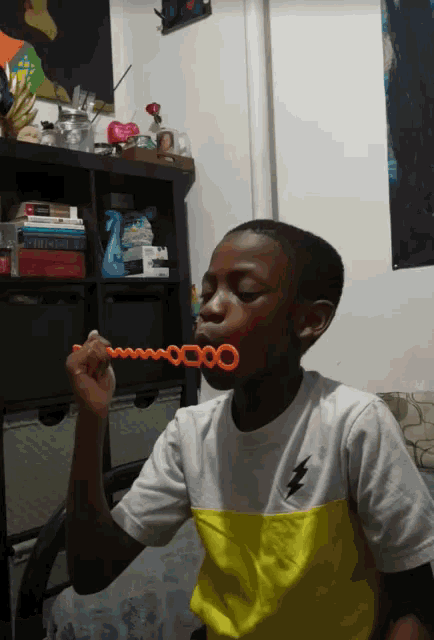a young boy blowing soap bubbles in a room with a poster on the wall that says ' entrance '