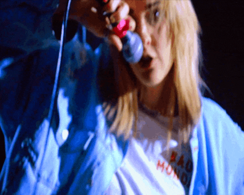 a woman is singing into a microphone and her shirt says bad monday