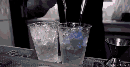 a bartender is pouring a drink into two plastic cups