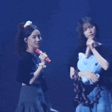 a group of girls are standing on a stage holding stuffed animals .