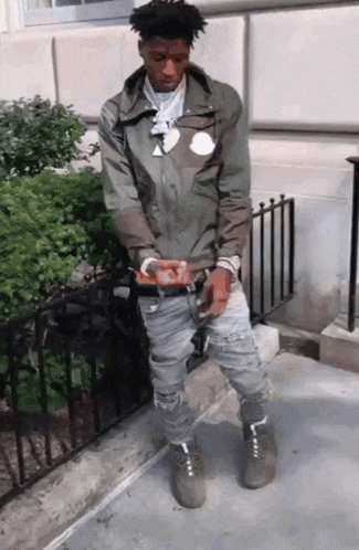 a man wearing a jacket with the word moncler on it is standing on a sidewalk