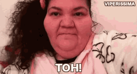 a woman with curly hair is making a funny face and saying `` toh '' .