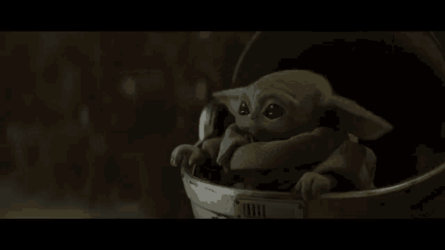 a baby yoda is sitting in a helmet .