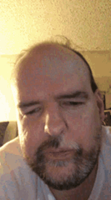 a man with a beard and a bald head is making a funny face