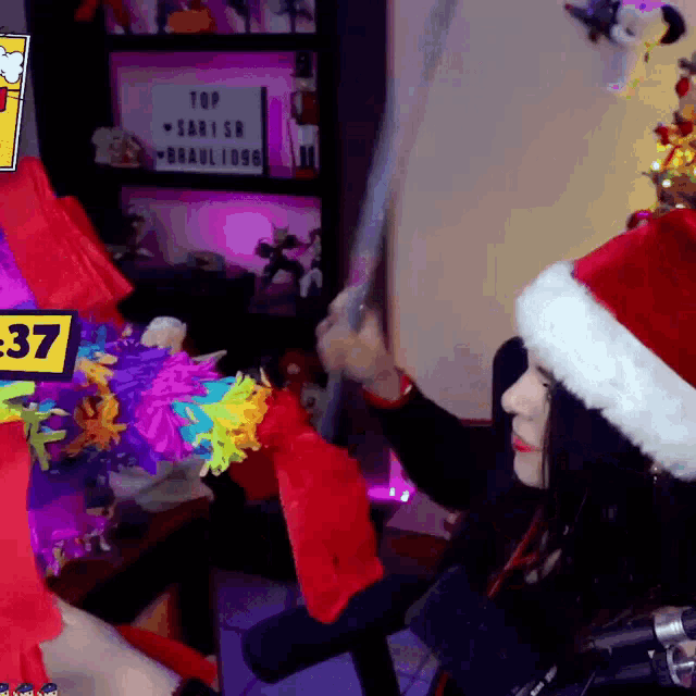 a woman wearing a santa hat holds a sword in front of a sign that says top