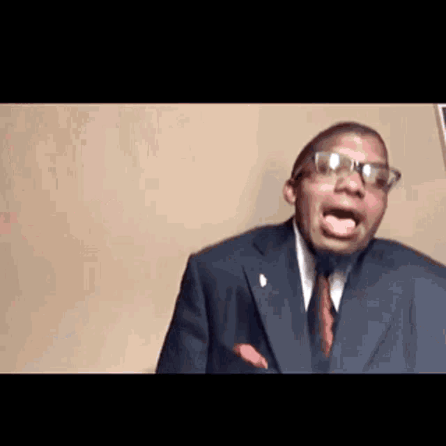 a man in a suit and tie is making a funny face with his mouth open .