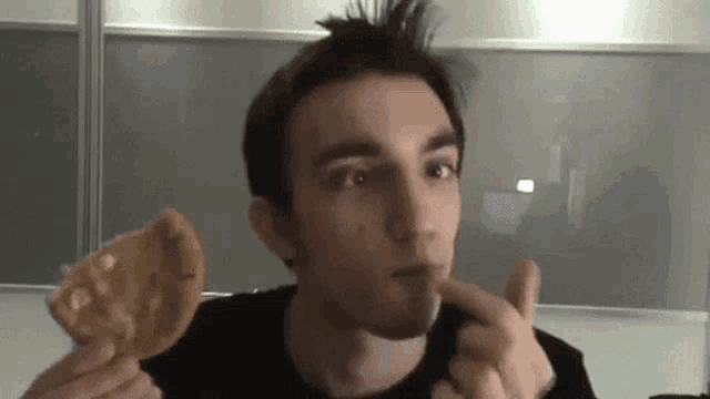 a man in a black shirt is eating a cookie