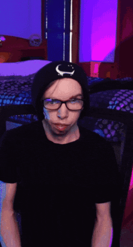 a person wearing glasses and a hat with a crescent moon on it is taking a selfie