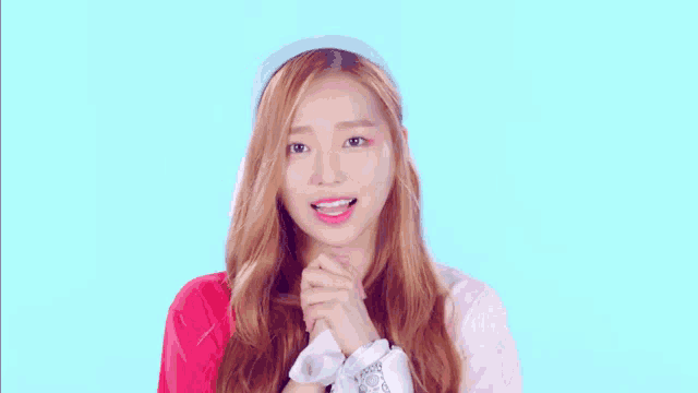 a girl wearing a red shirt and a blue headband holds her hands up in the air