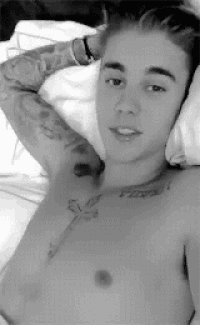 a shirtless man with a tattoo on his chest is laying on a bed .