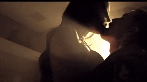 a man and a woman are kissing in the dark in a room .