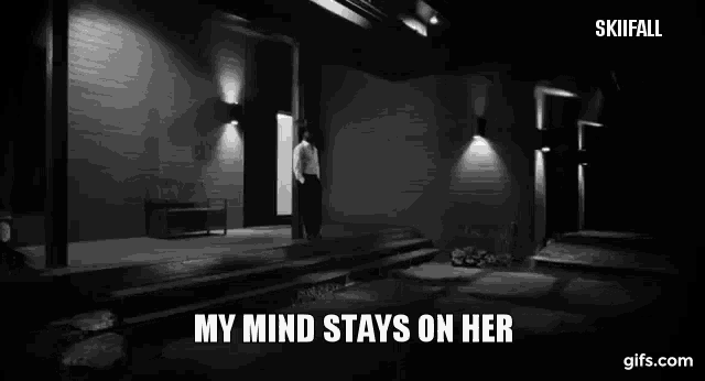 a black and white photo of a man standing in front of a building with the words my mind stays on her