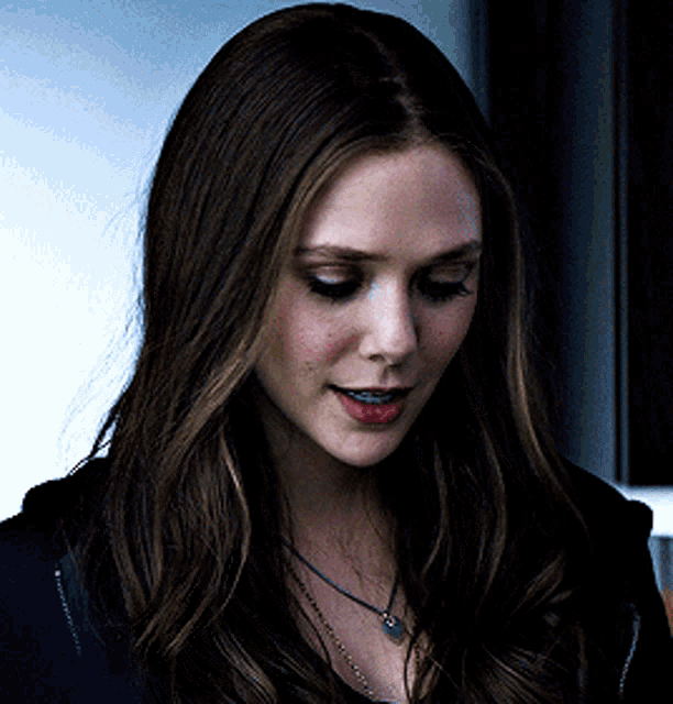 a close up of a woman 's face with long hair and a necklace