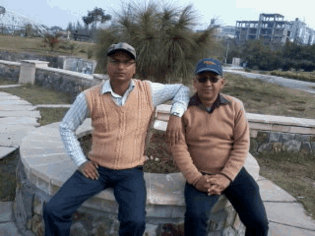 two men are posing for a picture while sitting on a stone ledge