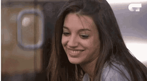 a woman with long hair is smiling and looking at the camera in a blurry photo .